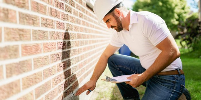 man with a white hard hat holding a clipboard, inspect house AdobeStock scaled